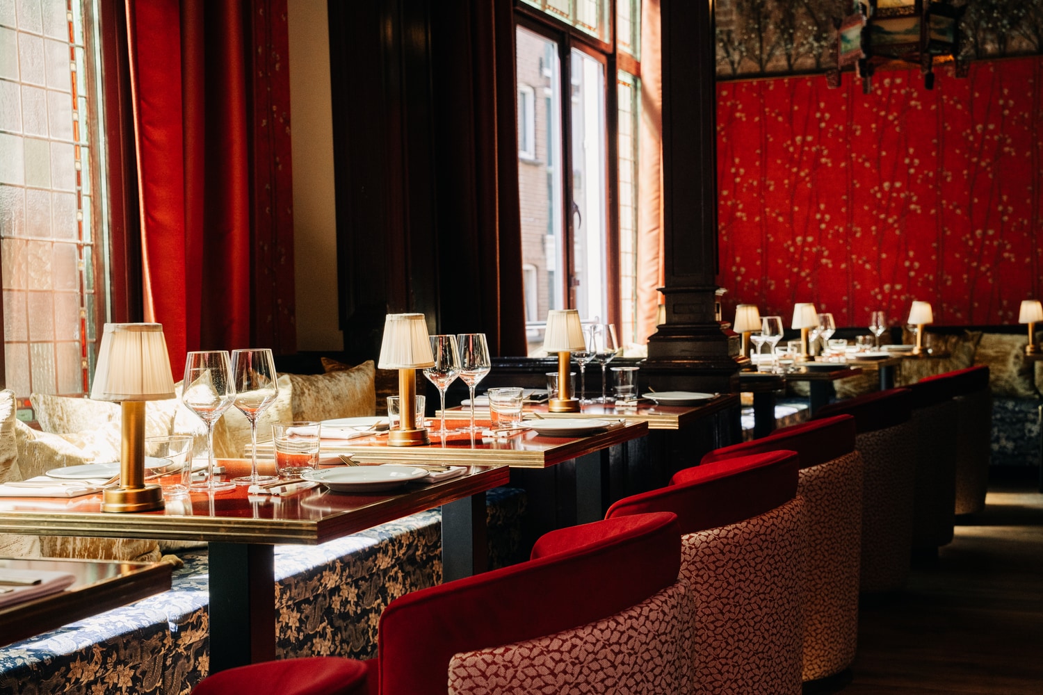 Dining room with red velvet banquettes and tables set along the windows