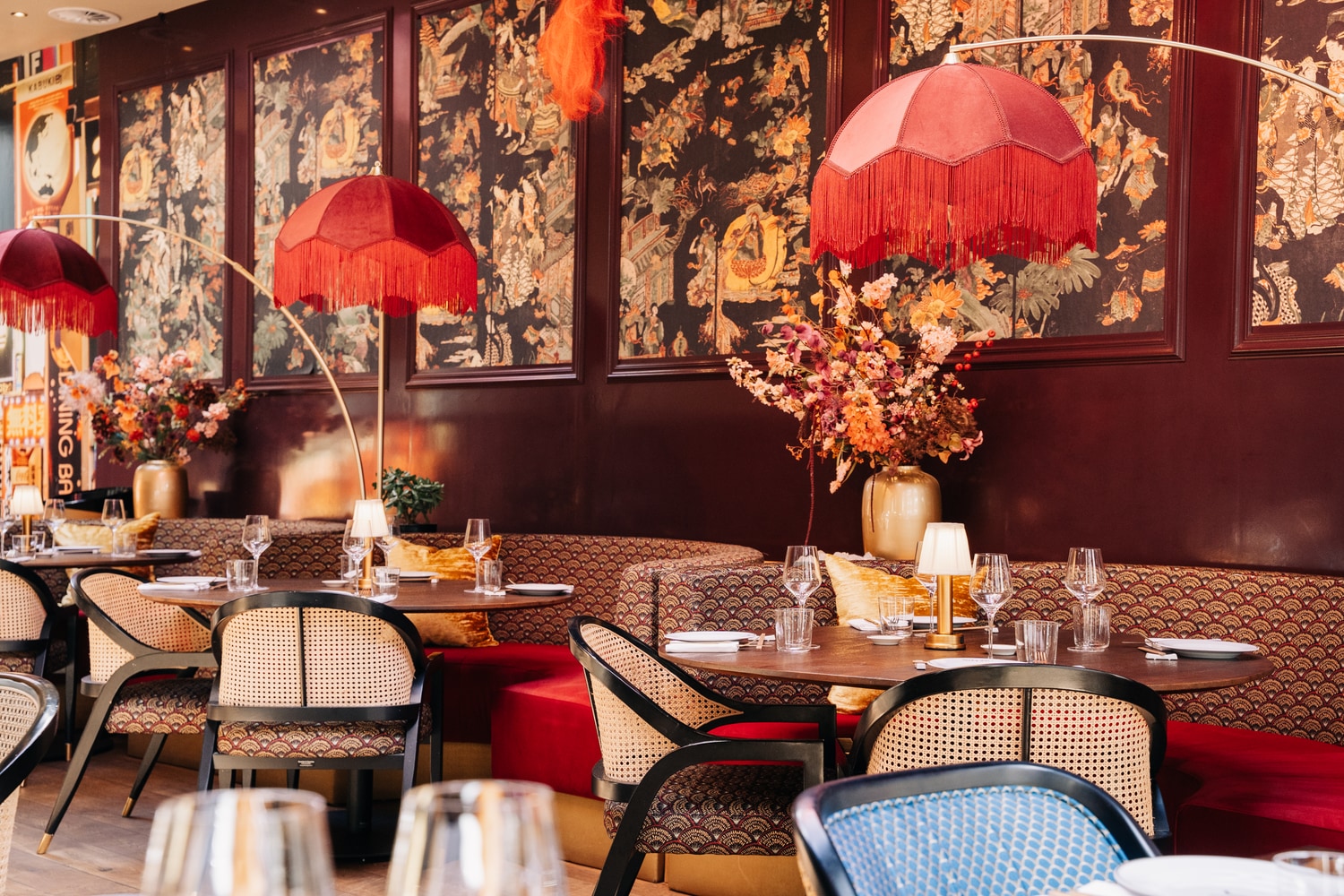 Dining room with red fringed pendant lamps above rattan chairs
