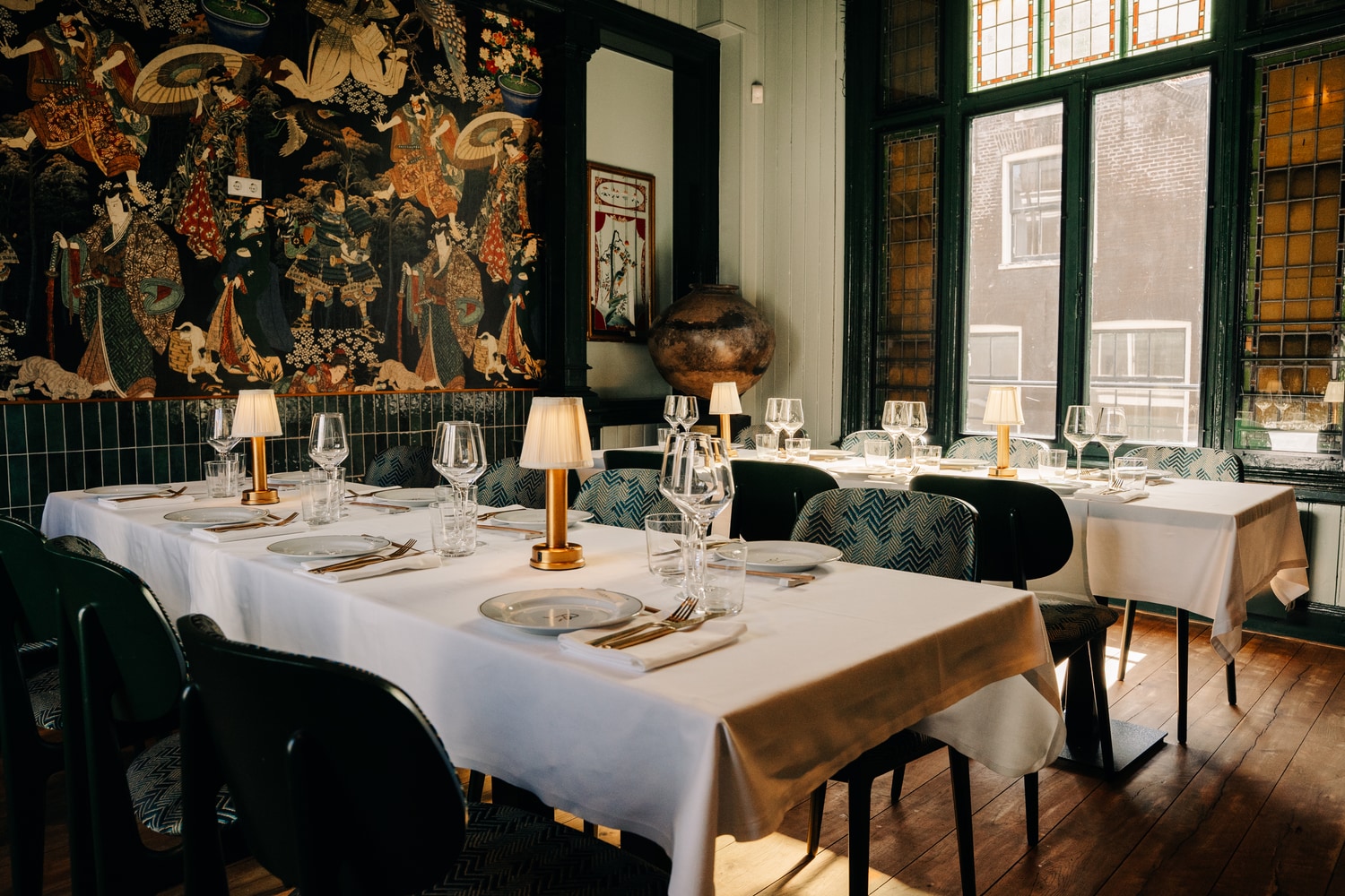 The private dining room, one long table set beneath a tapestry wall